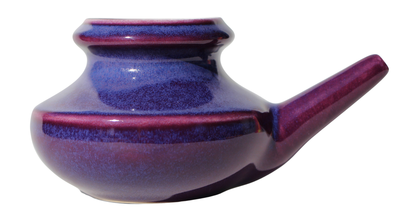 Purple ceramic neti pot on a white background
