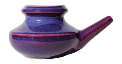 Purple ceramic neti pot on a white background